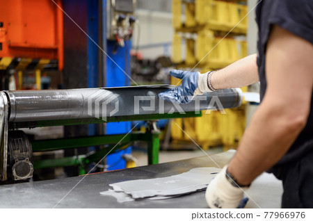 Close-up of male hands in working gloves working in metal processing factory. Worker using machinery 77966976