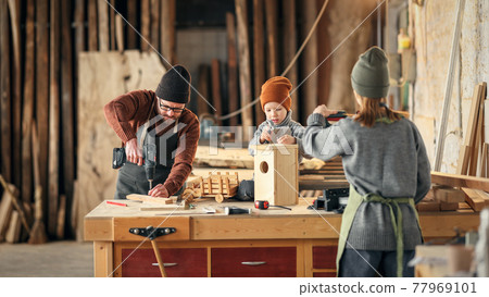 Parents and kid making  wooden bird house in craft workplace 77969101