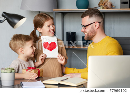 Little kids son and daughter making surprise for dad on Father's Day and giving him handmade postcard with drawn heart 77969102