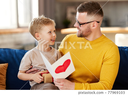 Cheerful father and son celebrating Fathers Day together at home 77969103