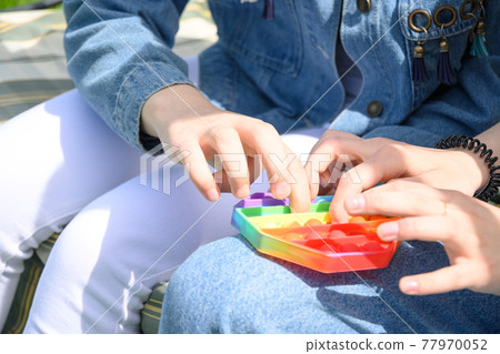 Girls playing with popular silicone antistress pop it hexagon toy. 77970052