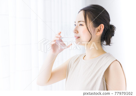 一個年輕的女人喝礦泉水 一個年輕的女人喝礦泉水 77970102