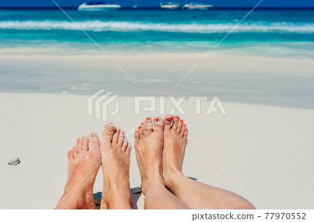Young woman looking down of view perspective on bare feet standing in white sand 77970552