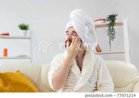 Bearded man applying eye patches on his face. Wrinkles and face home care for men. Bearded man applying eye patches on his face. Wrinkles and face home care for men. 77971214
