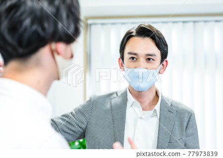 A businessman wearing a mask and having a meeting 77973839