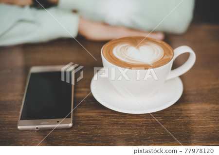 Man hand with cup of latte art coffee and smartphone at cafe bar. Man hand with cup of latte art coffee and smartphone at cafe bar. 77978120
