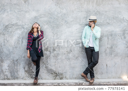 Couple talking to mobile on brick wall, vintage, grunge background. Couple talking to mobile on brick wall, vintage, grunge background. 77978141
