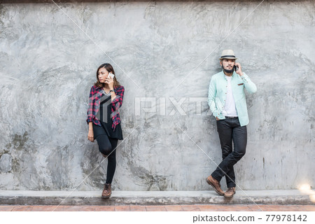 Couple talking to mobile on brick wall, vintage, grunge background. 77978142