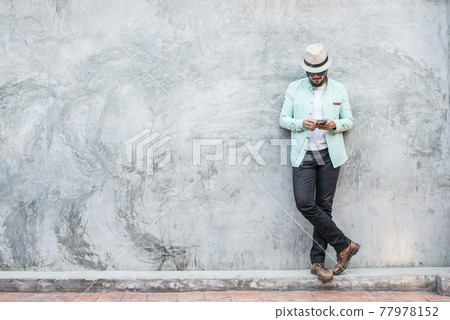 Portrait of handsome young hipster man using smartphone against a grunge bricks wall background. 77978152