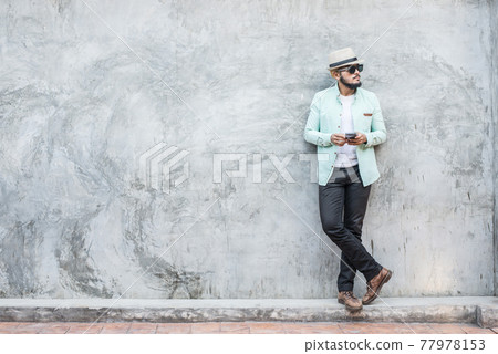 Portrait of handsome young hipster man using smartphone against a grunge bricks wall background. Portrait of handsome young hipster man using smartphone against a grunge bricks wall background. 77978153