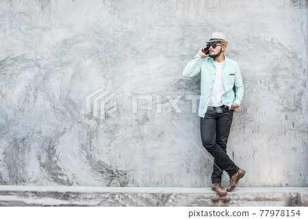 Portrait of handsome young hipster man using smartphone against a grunge bricks wall background. Portrait of handsome young hipster man using smartphone against a grunge bricks wall background. 77978154