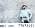 Portrait of handsome young hipster man listening to music against a grunge bricks wall background. 77978159