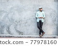 Portrait of handsome young hipster man listening to music against a grunge bricks wall background. 77978160