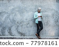 Portrait of handsome young hipster man listening to music against a grunge bricks wall background. 77978161