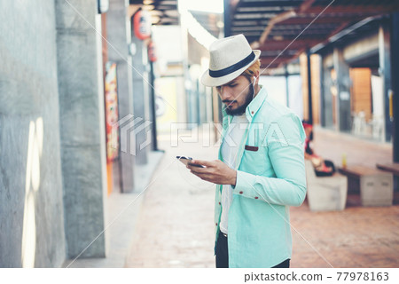 Hipster man listening music with his smartphone on the street in urban. Hipster man listening music with his smartphone on the street in urban. 77978163
