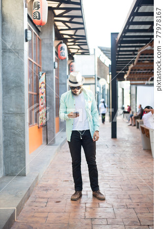 Hipster man listening music with his smartphone on the street in urban. 77978167