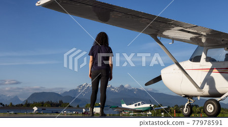 Adventurous woman standing by the Airplane parked at the Airport 77978591
