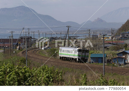A blunt train (Kiha 40 series) running with Mt. Usu, Mt. Showa-shinzan, and Mt. 77980054