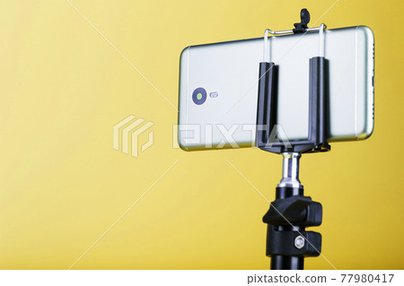 Smartphone on a tripod on a yellow background for blogging. Smartphone on a tripod on a yellow background for blogging. 77980417