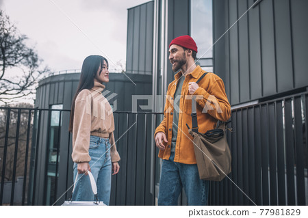 Young man and woman in casual clothes talking outside Young man and woman in casual clothes talking outside 77981829