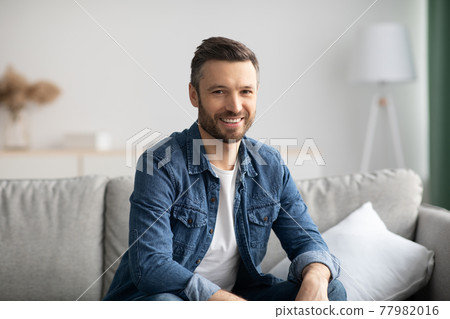 Happy bearded man relaxing on sofa at home Happy bearded man relaxing on sofa at home 77982016