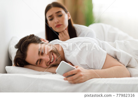 Wife Spying While Cheating Husband Texting On Cellphone In Bedroom Wife Spying While Cheating Husband Texting On Cellphone In Bedroom 77982316