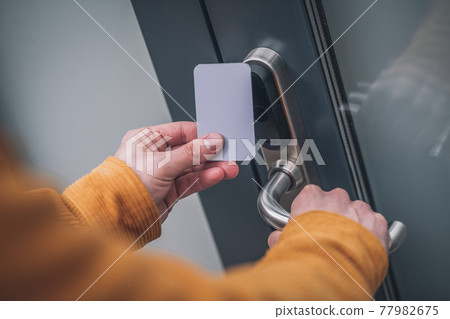 Bearded young man opening the door with an access card Bearded young man opening the door with an access card 77982675
