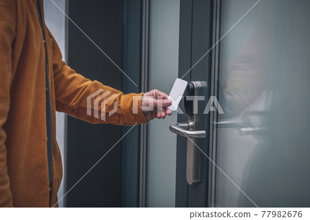 Bearded young man opening the door with an access card 77982676