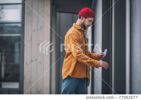 Bearded young man opening the door with an access card Bearded young man opening the door with an access card 77982677