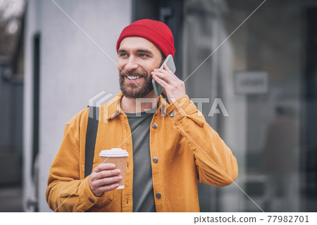 Man in an orange jacket with a phone in his hands Man in an orange jacket with a phone in his hands 77982701