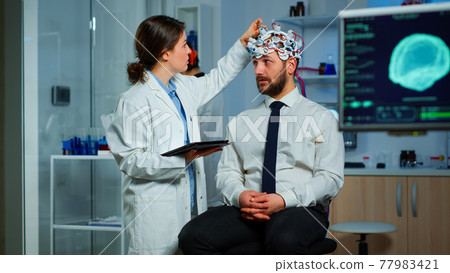 Man sitting on neurological chair with brainwave scanning headset Man sitting on neurological chair with brainwave scanning headset 77983421