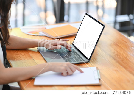 Cropped shot of businesswoman analyzing business data and while working with laptop computer in office. Cropped shot of businesswoman analyzing business data and while working with laptop computer in office. 77984026
