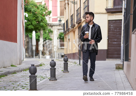 caucasian man with a beard, having a coffee to go in the city caucasian man with a beard, having a coffee to go in the city 77986458