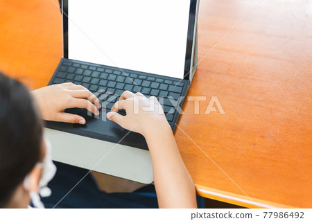 Young student with protective mask hands typing on laptop. Young student with protective mask hands typing on laptop. 77986492