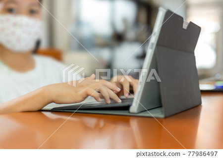 Young child student with protective mask hands typing on laptop. 77986497