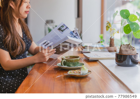 Female reading a magazine and drink coffee in cafe. 77986549