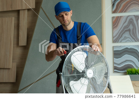 An electrician repairs the cooling fan. Repair of equipment in the room An electrician repairs the cooling fan. Repair of equipment in the room 77986641