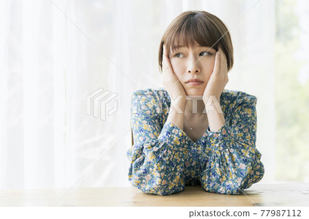 一個拿著臉頰棒的年輕女人，她的憂慮和想法的形象 77987112