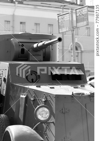 A fragment of an armored vehicle against background of a blurred bus stop sign 77987135