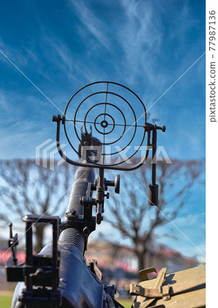 fragment of an anti aircraft machine gun, a round sight is aimed at clouds sky 77987136