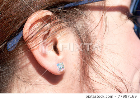 Fragment of a woman face, an ear with a glass earring Fragment of a woman face, an ear with a glass earring 77987169