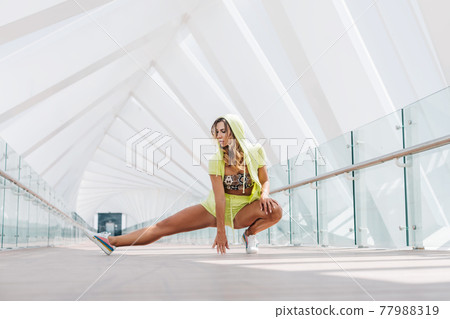 A young woman in sportswear performs exercises during a morning workout. Sports, fitness, healthy lifestyle A young woman in sportswear performs exercises during a morning workout. Sports, fitness, healthy lifestyle 77988319