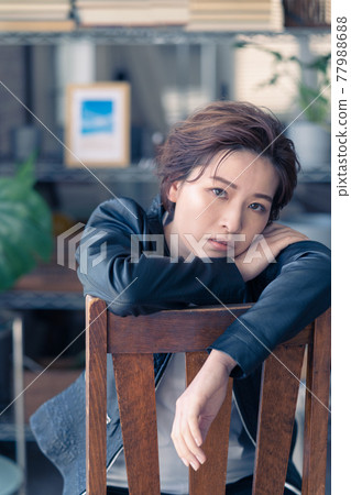 Genderless LGBT woman in a leather jacket sitting on a chair 77988688