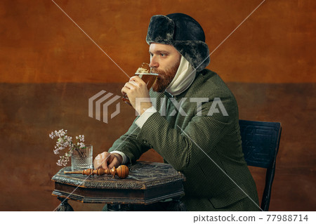 Portrait of red headed and bearded man playing famous artist isolated over dark bacground. Eras comparison 77988714