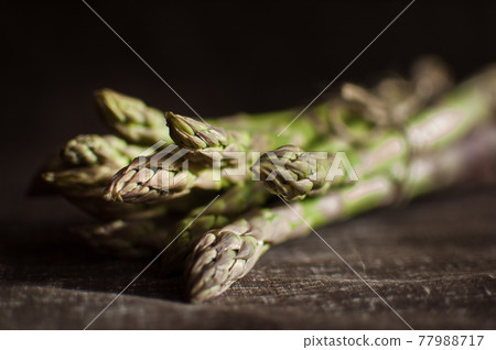 Bunch of fresh green asparagus on dark wooden table, healthy eating, seasonal products Bunch of fresh green asparagus on dark wooden table, healthy eating, seasonal products 77988717