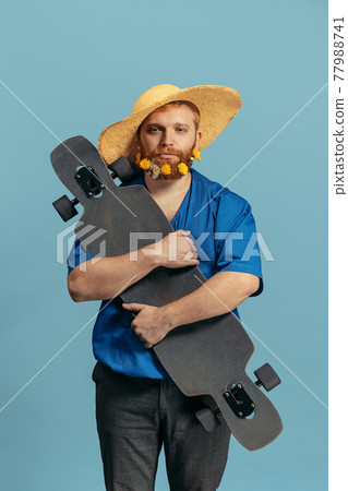 Young red headed and bearded man in straw hat standing isolated over blue bacground. Eras comparison 77988741