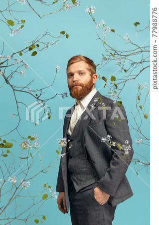 Portrait of young red headed and bearded man acting famous artist isolated over blue floral bacground 77988776