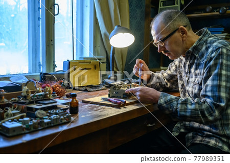 Male amateur radio operator repairing an old radio receiver Male amateur radio operator repairing an old radio receiver 77989351