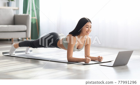 Fit Asian Woman Training At Home With Laptop, Making Plank Exercise Fit Asian Woman Training At Home With Laptop, Making Plank Exercise 77991296
