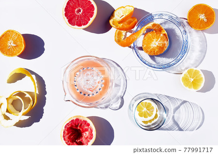 Summer creative flat lay with fresh citrus fruits and juce on sunlight with hard shadows. Minimal food creative concept. Summer creative flat lay with fresh citrus fruits and juce on sunlight with hard shadows. Minimal food creative concept. 77991717